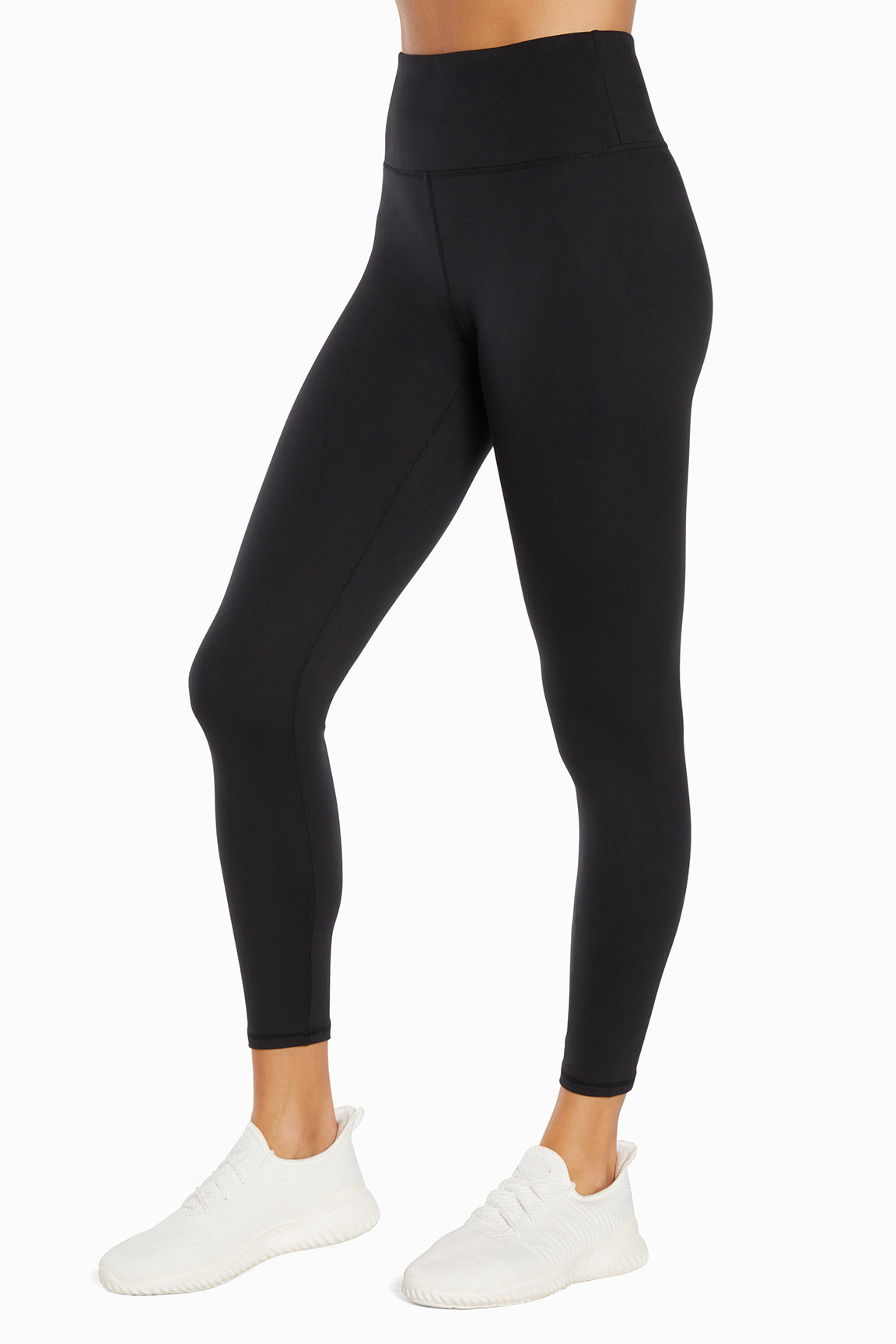 Side view of woman wearing black leggings on a white background.
