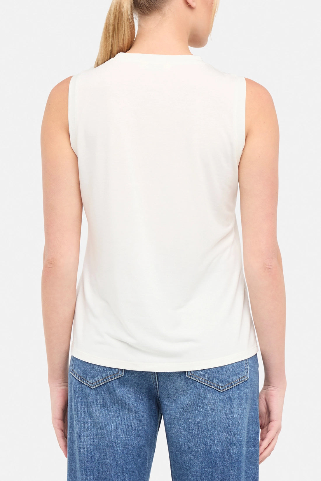 Back view of woman wearing a sleeveless shirt on a plain background.