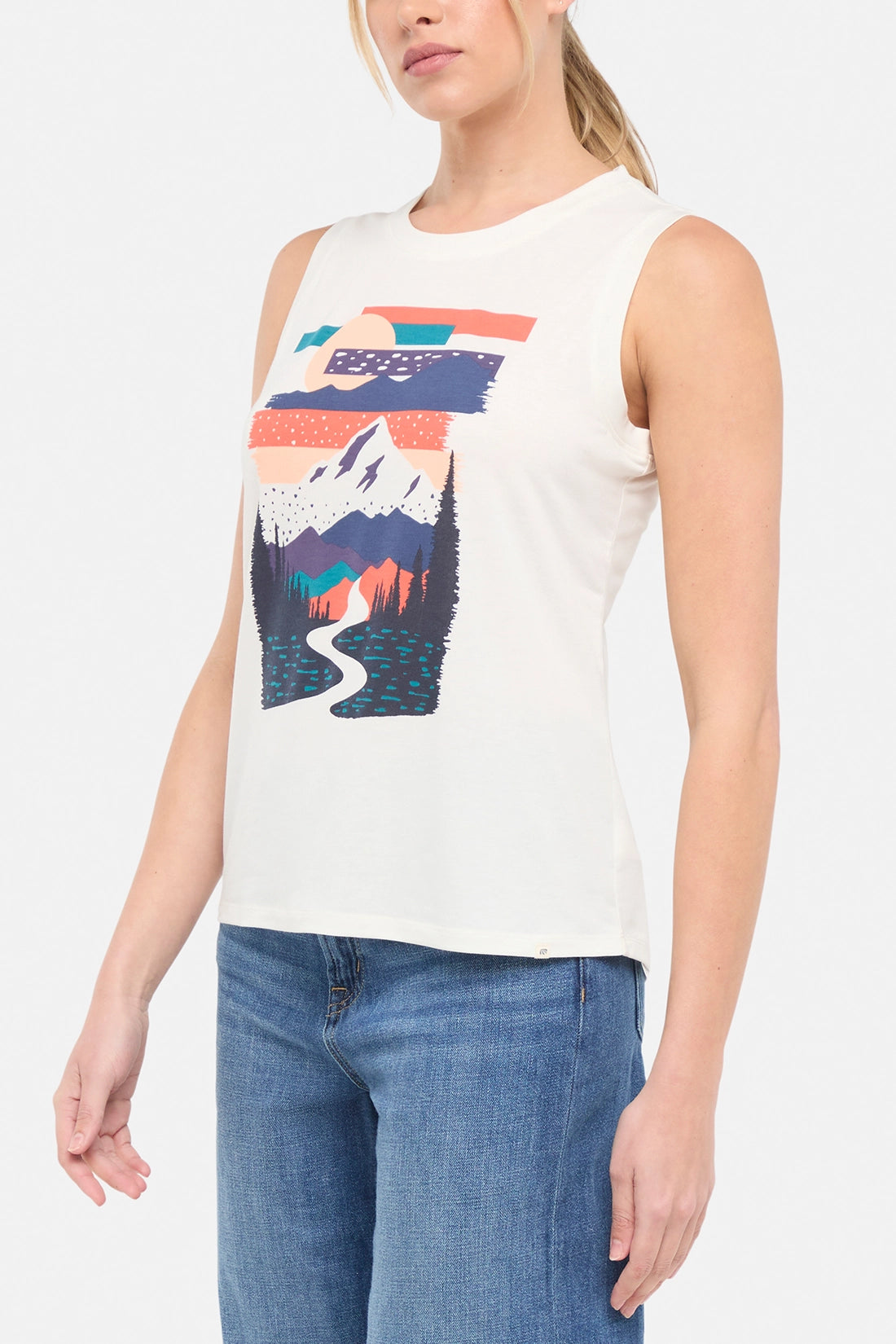 Side view of woman wearing a sleeveless shirt with a mountain graphic design on a plain background.