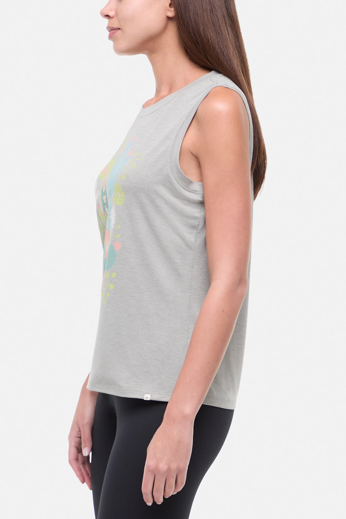 Side view of woman wearing a sleeveless gray top with colorful floral and cactus design on a white background.