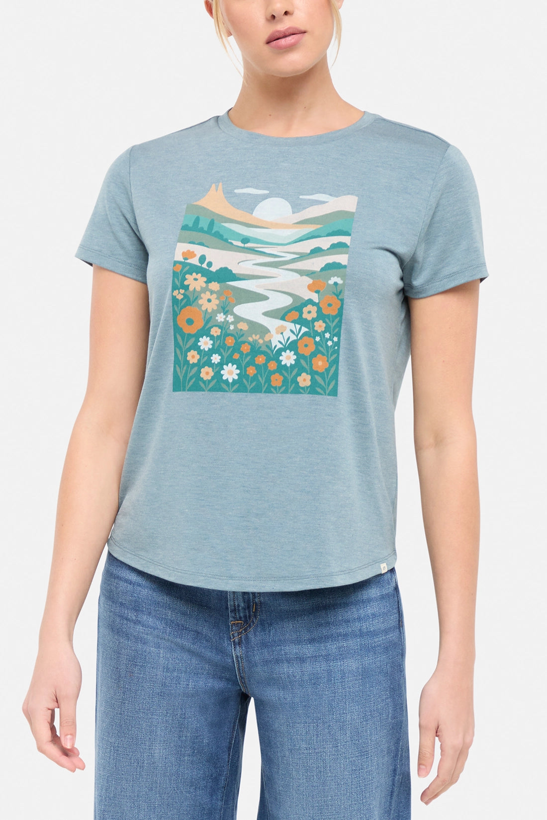 Front view of woman wearing a blue t-shirt with nature-themed graphic design on a white background.