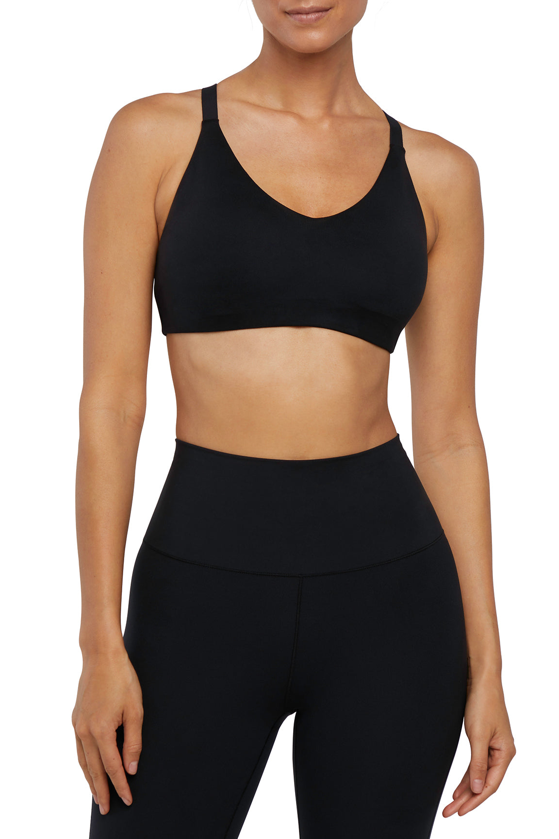 Front view of woman wearing a black sports bra and leggings on a white background.