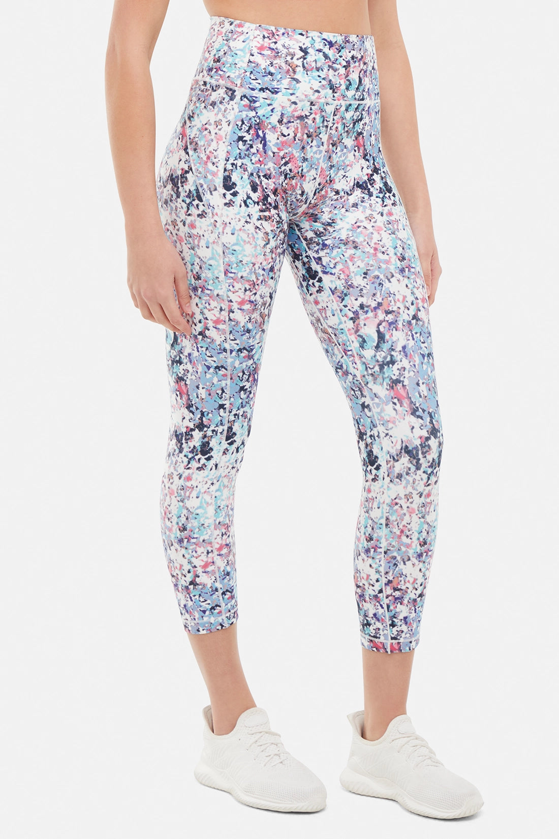 front view of woman wearing colorful floral leggings on a white background.