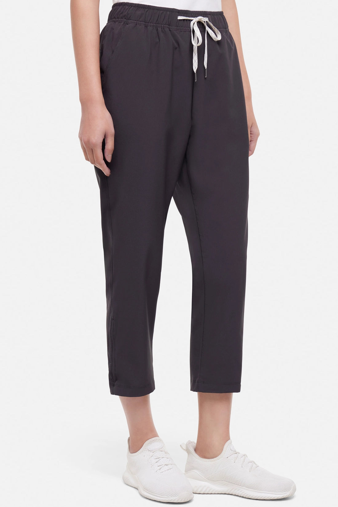 Front view of woman wearing black cropped pants with a white drawstring on a white background.