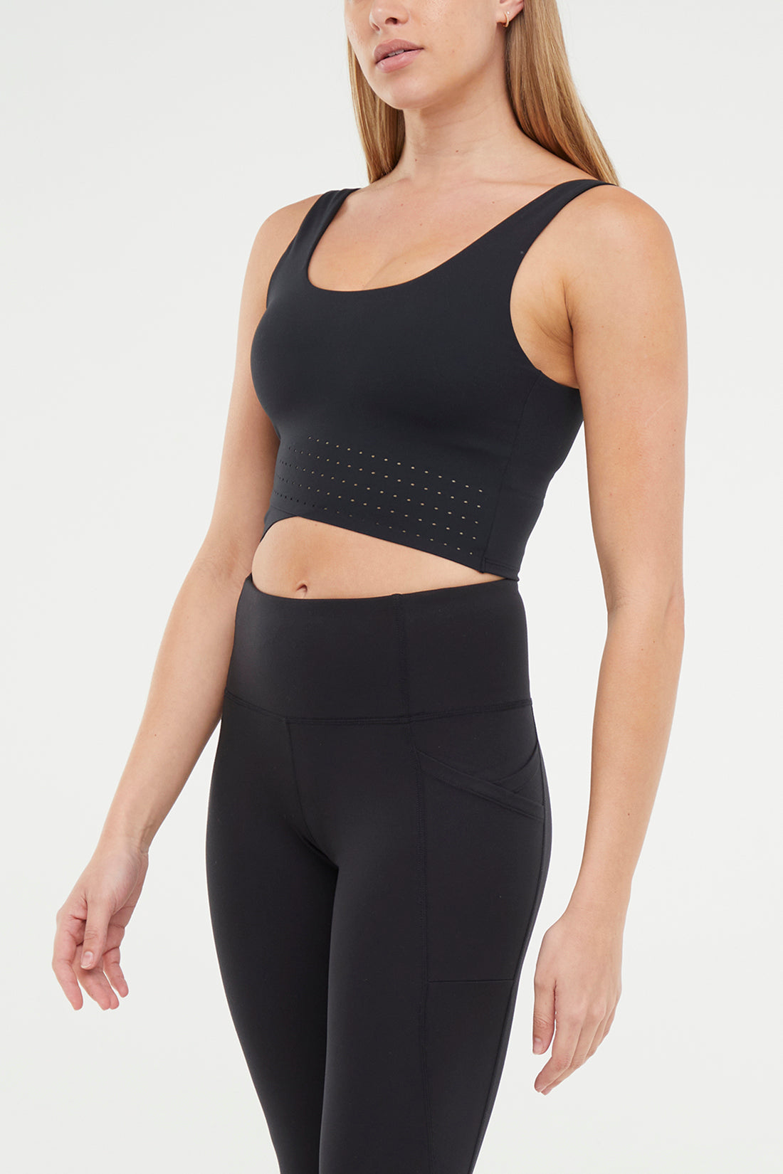 Front view of woman wearing a black sports bra and black leggings on a white background.