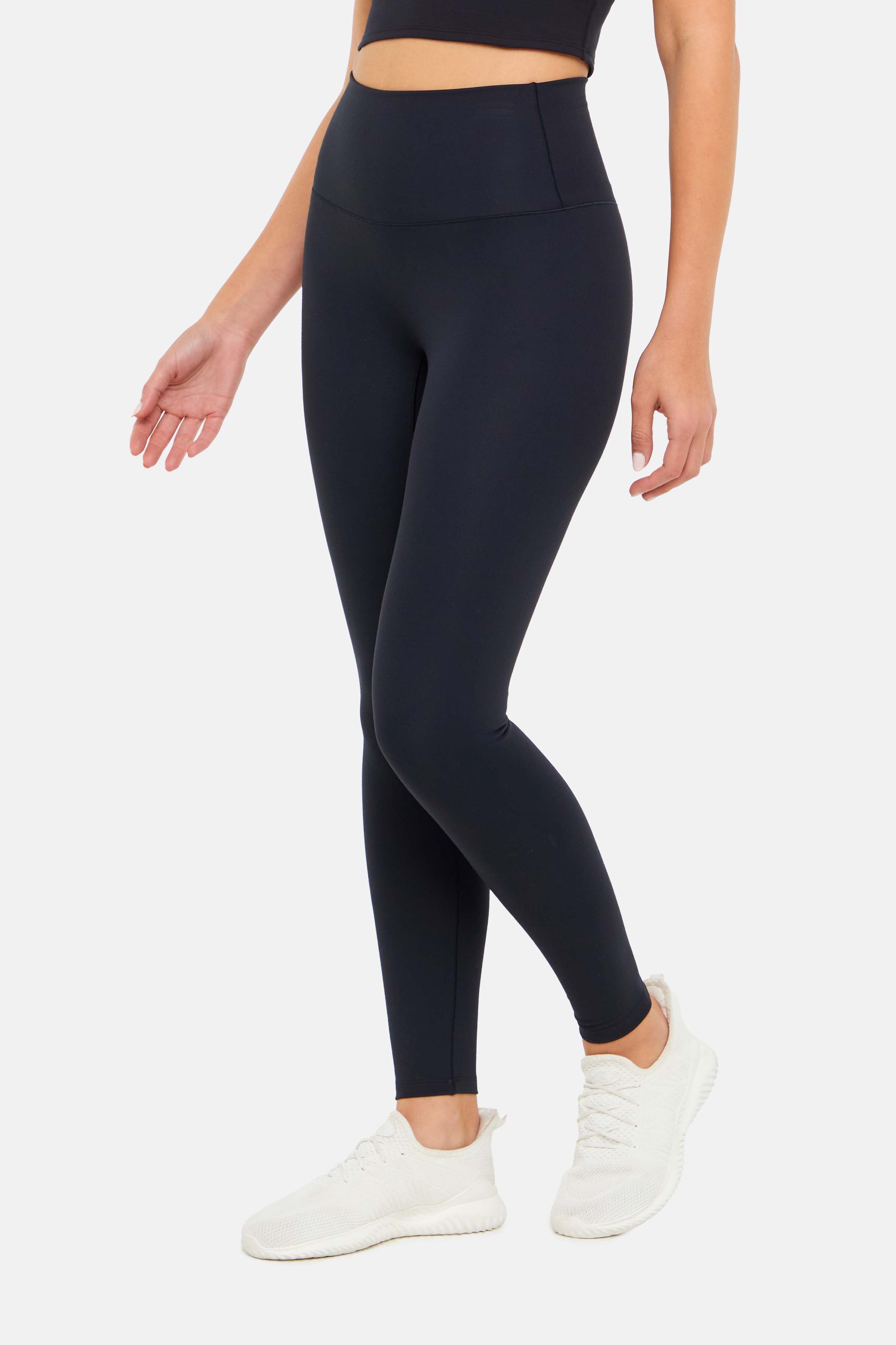 Side view of woman wearing black leggings on a white background.