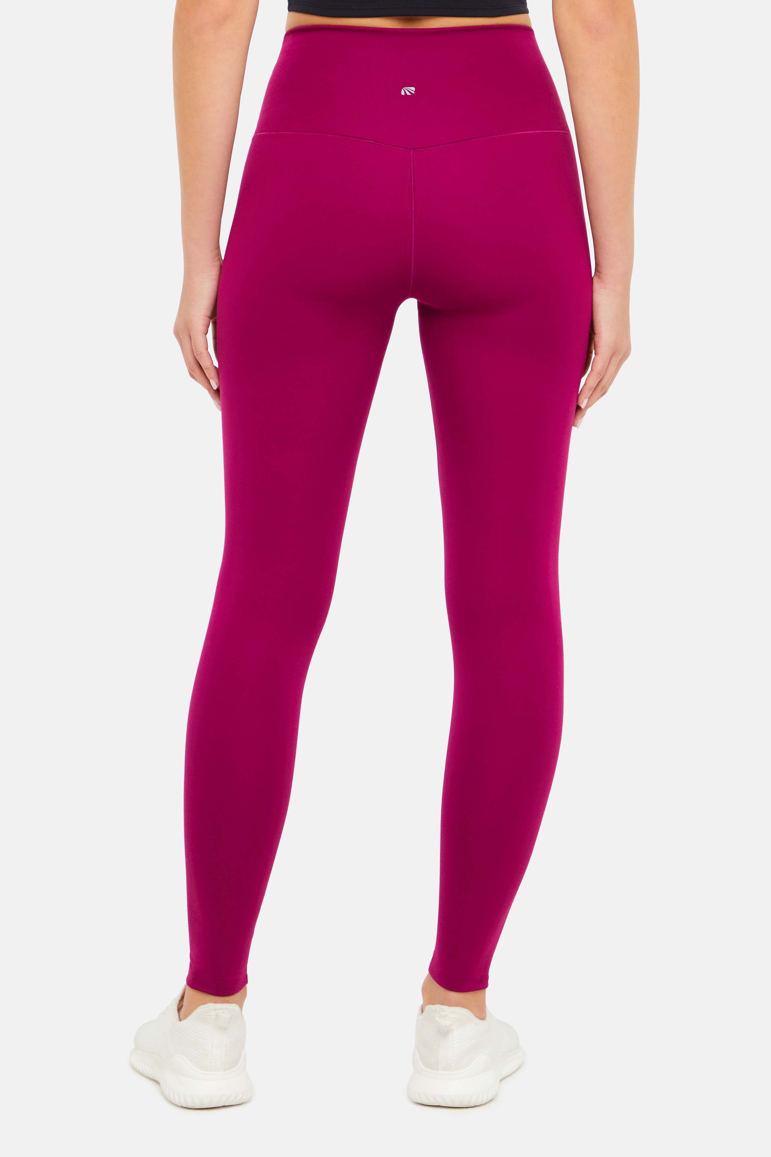 Back view of woman wearing bright burgundy leggings on a white background.