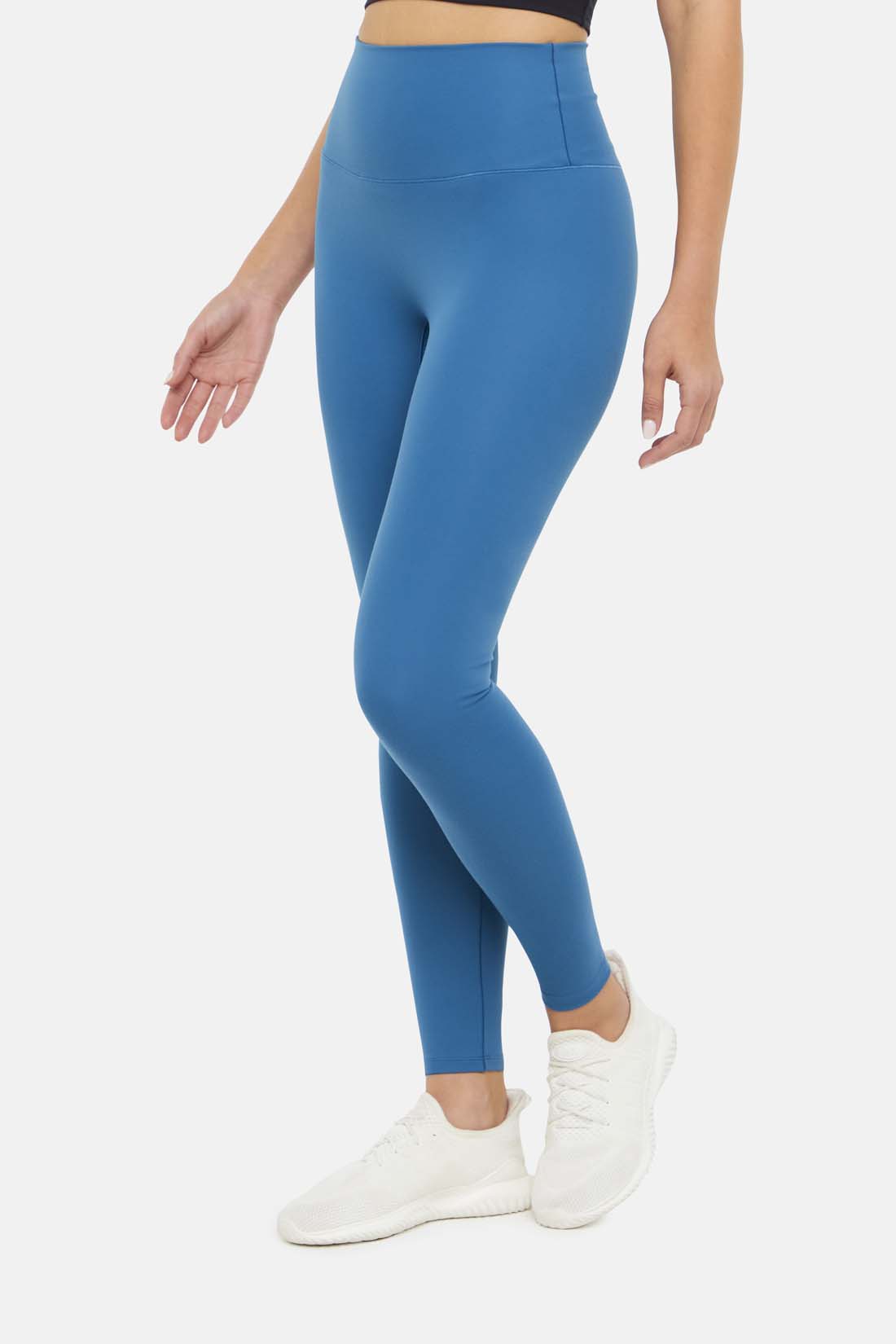 Side view of woman wearing bright blue leggings on a white background.