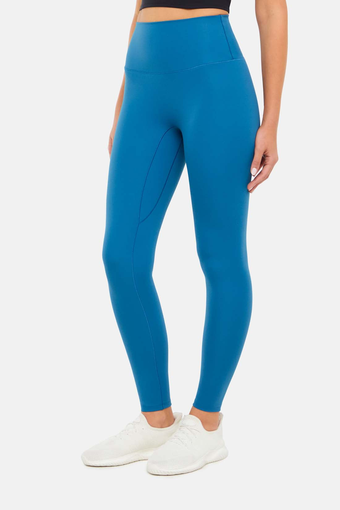 Front view of woman wearing bright blue leggings on a white background.