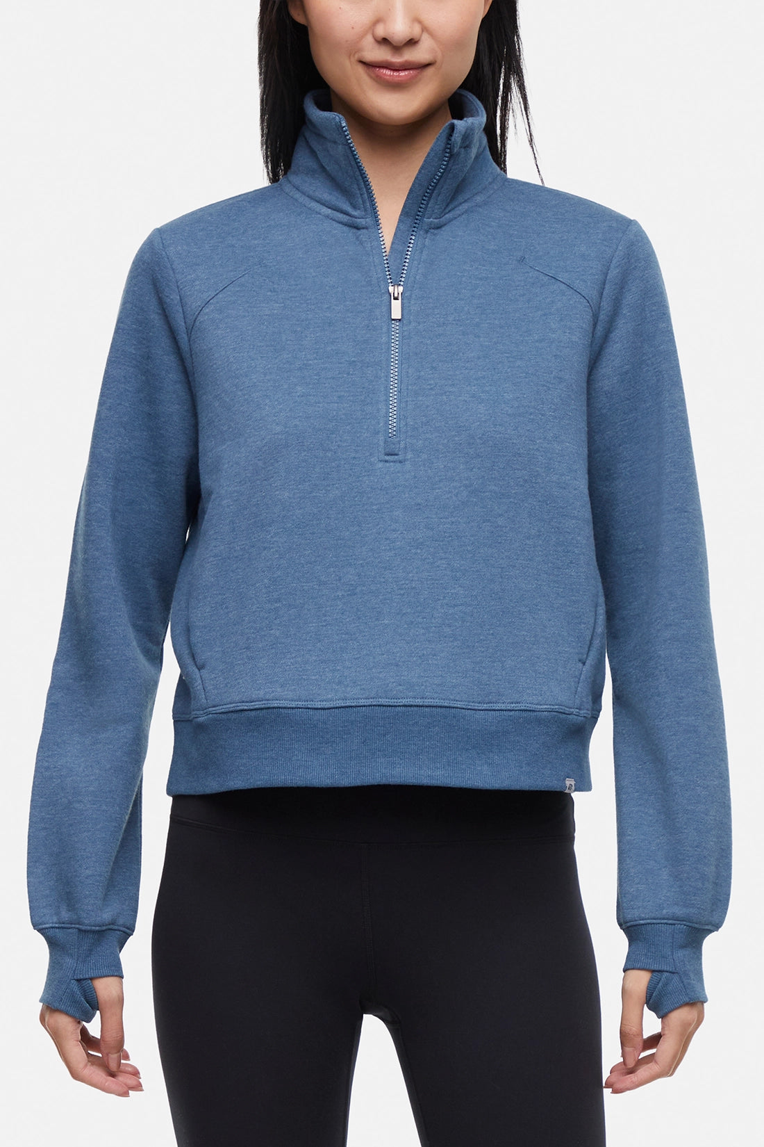 Front view of woman wearing heather blue half-zip pullover with thumbholes on a white background.
