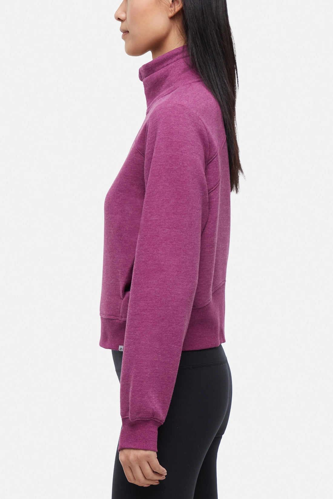 Side view of woman wearing burgundy half-zip pullover with thumbholes on a white background.