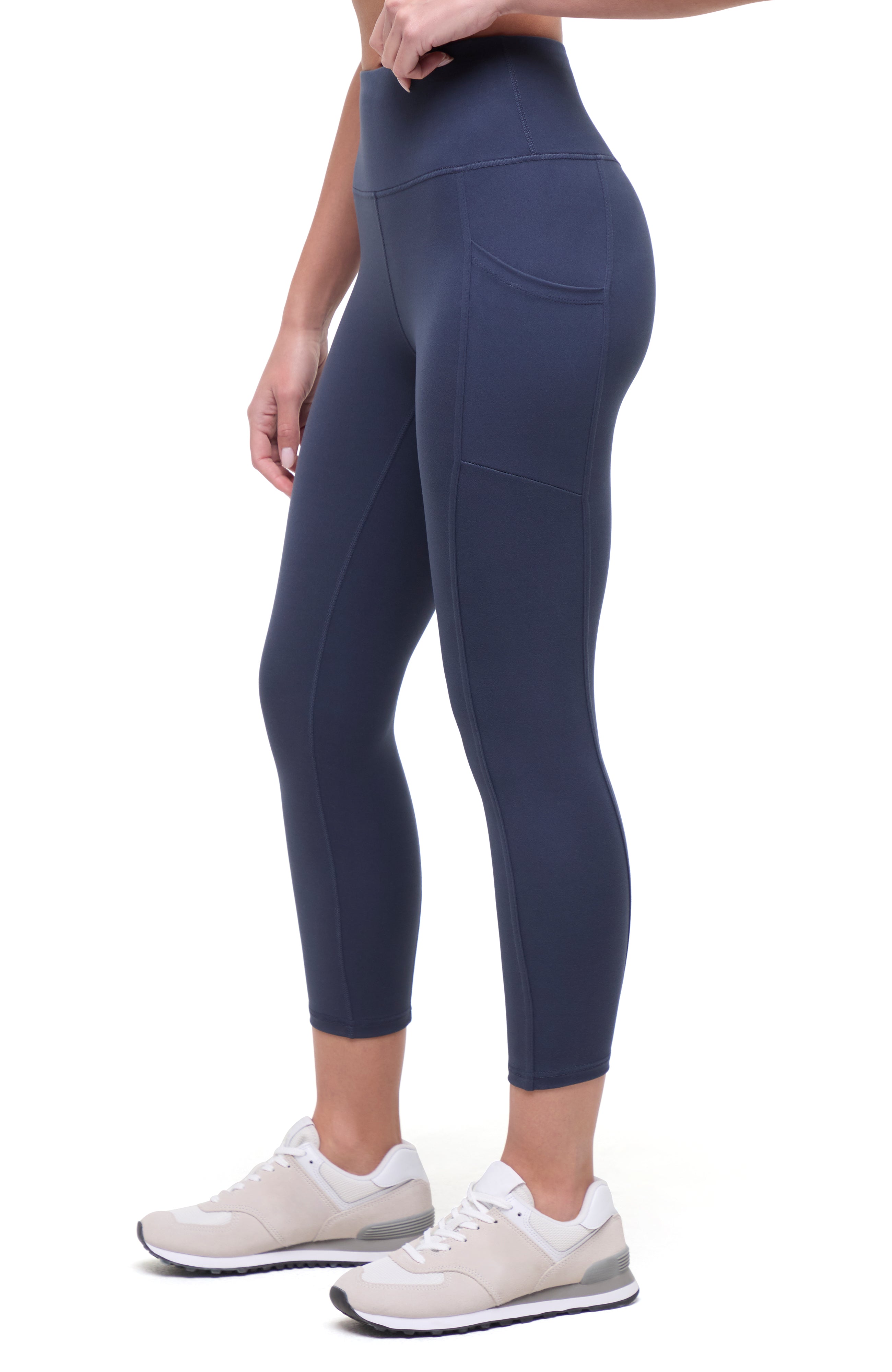 Side view of woman wearing navy blue leggings on a white background.