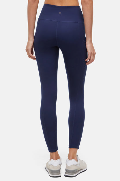 Back view of woman wearing navy blue leggings with a white background. 