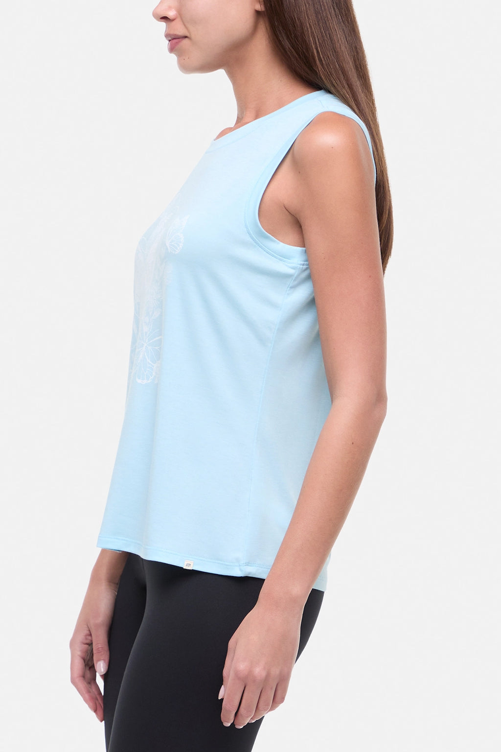 Side view of woman wearing a light blue sleeveless top with white butterflies design on a plain background. #color_heather-ocean-current-butterfly-bunch