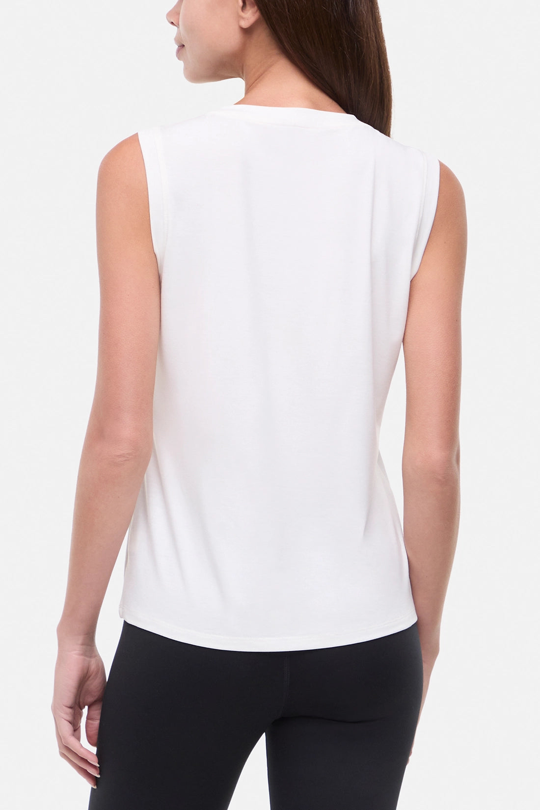 Back view of woman wearing white sleeveless shirt on a white background.
