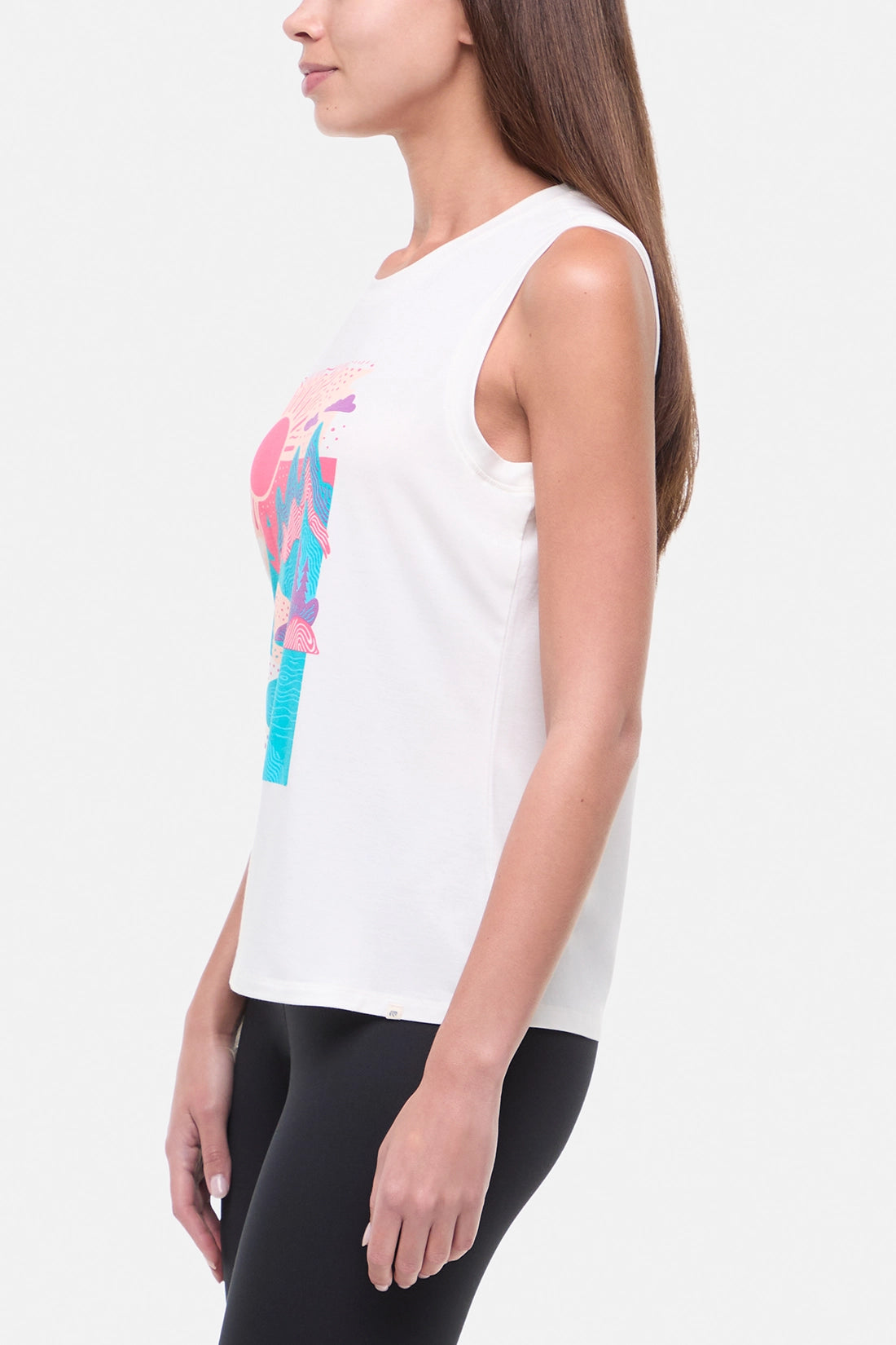 Side view of woman wearing white sleeveless shirt with a colorful nature graphic on a white background.