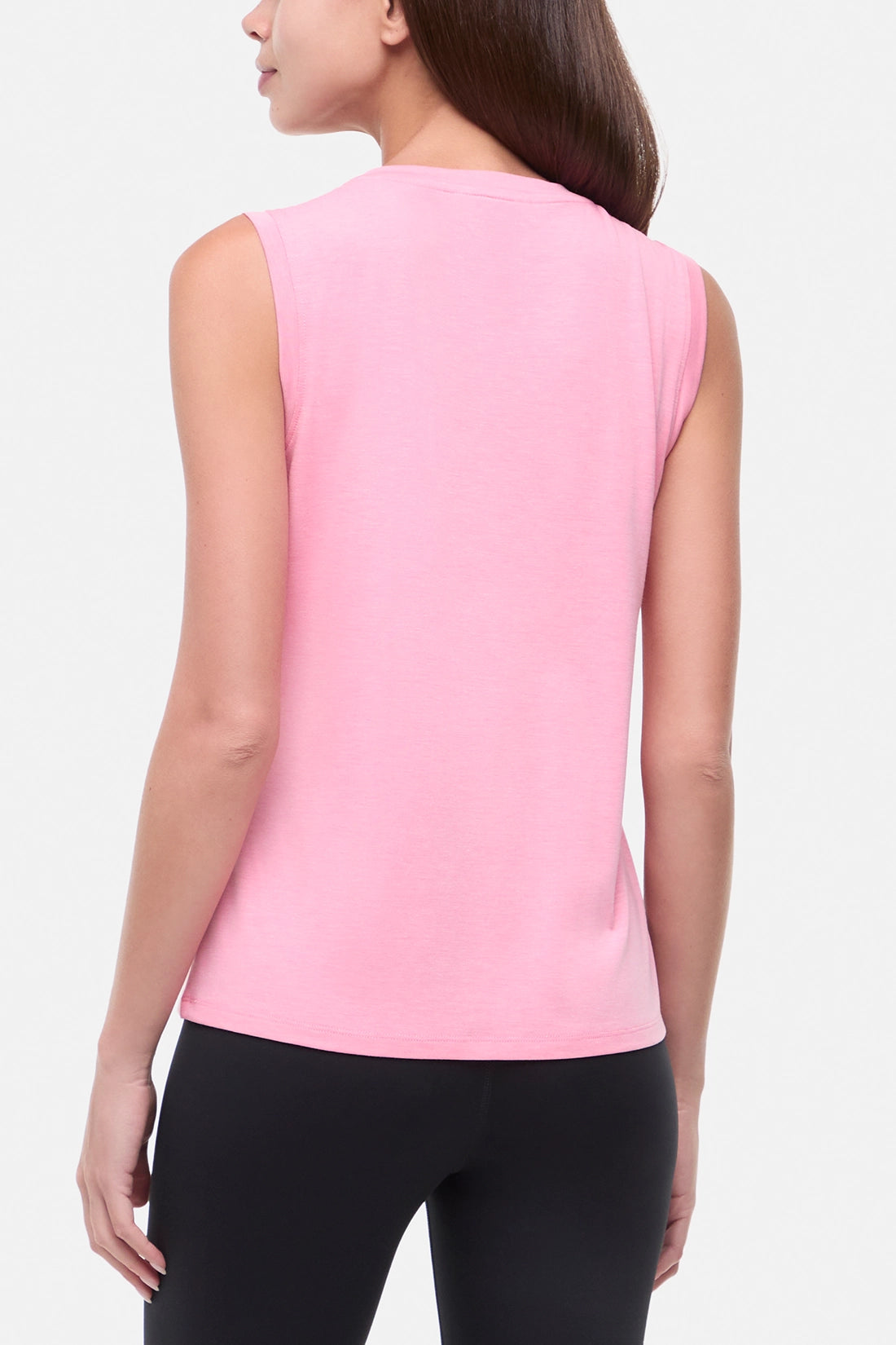 Back view of woman wearing a pink sleeveless top with a colorful floral and mountain design on a white background.