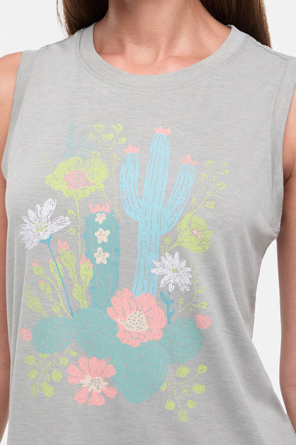 Close up view of woman wearing a sleeveless gray top with colorful floral and cactus design on a white background. 