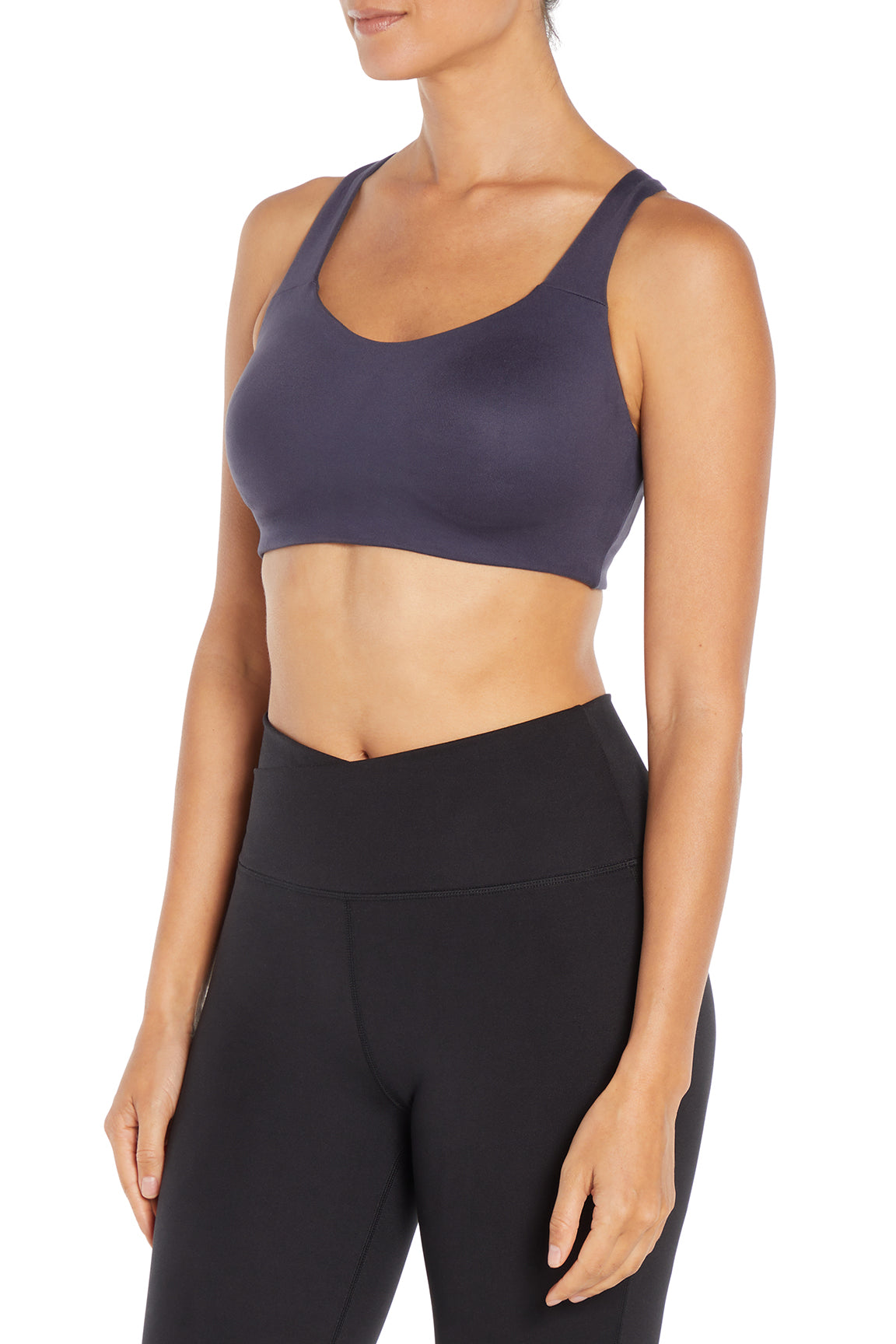 A woman wearing a dark slate purple sports bra and black high-waisted leggings, shown from the side against a plain white background.  
