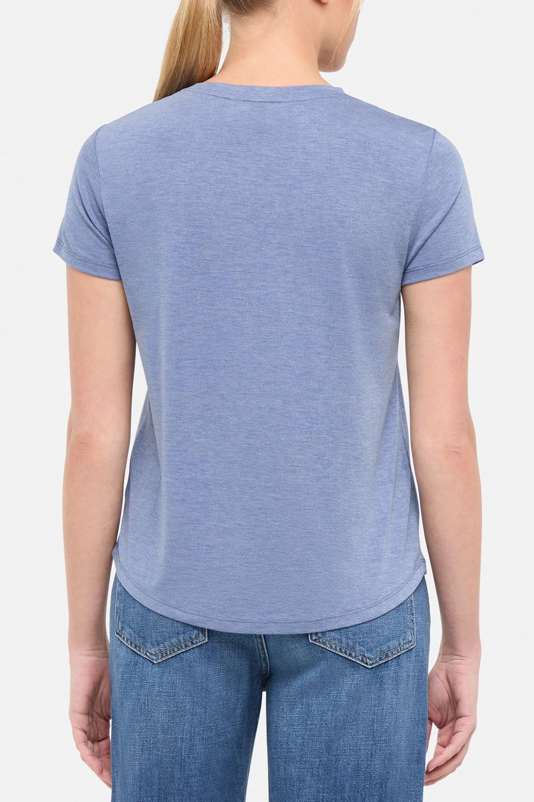 Back view of woman wearing a blue t-shirt on a white background. 