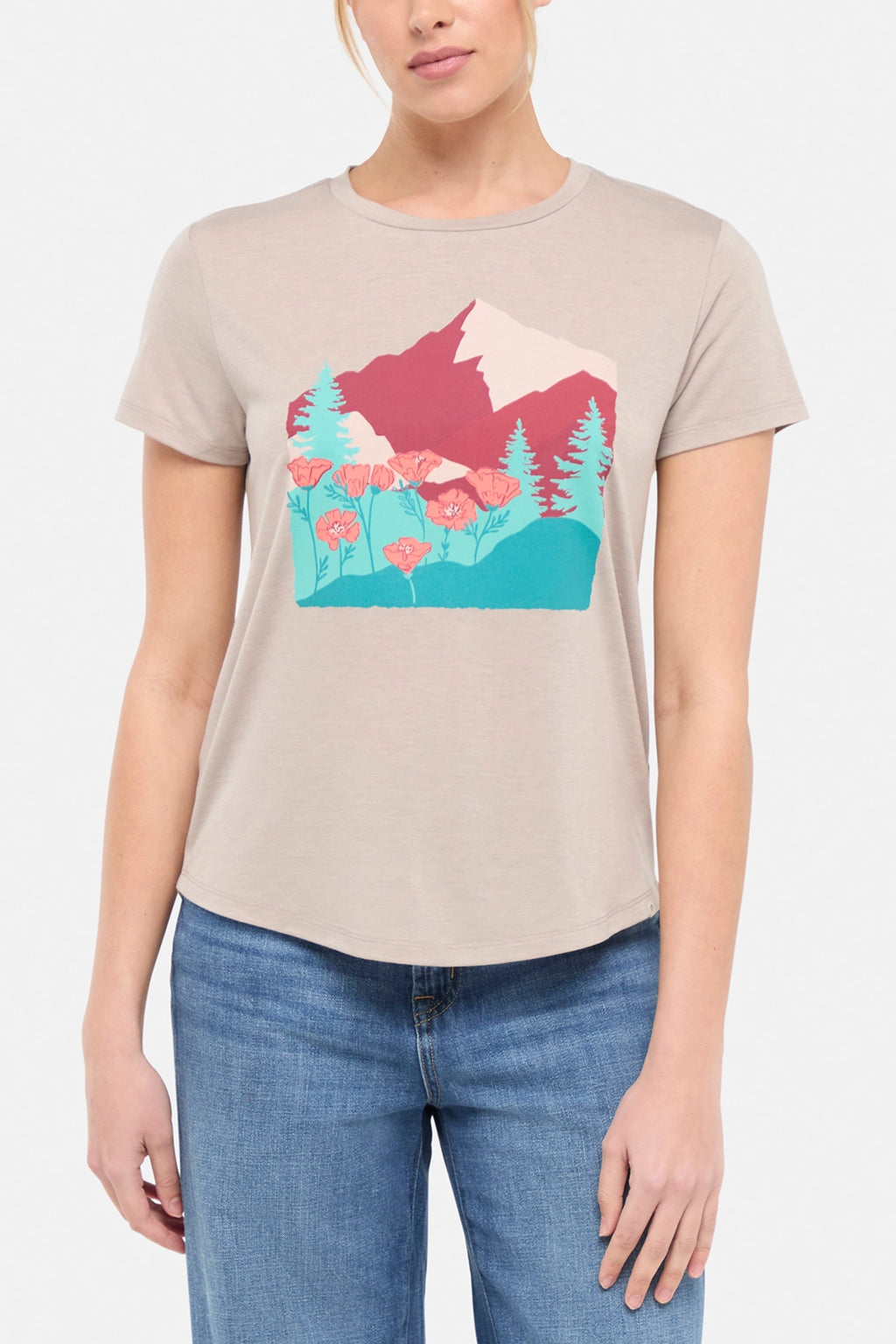 Front view of woman wearing a beige t-shirt with a graphic design of trees and poppy flowers, paired with blue jeans on white background. #color_heather-atmosphere-poppies-on-mountains