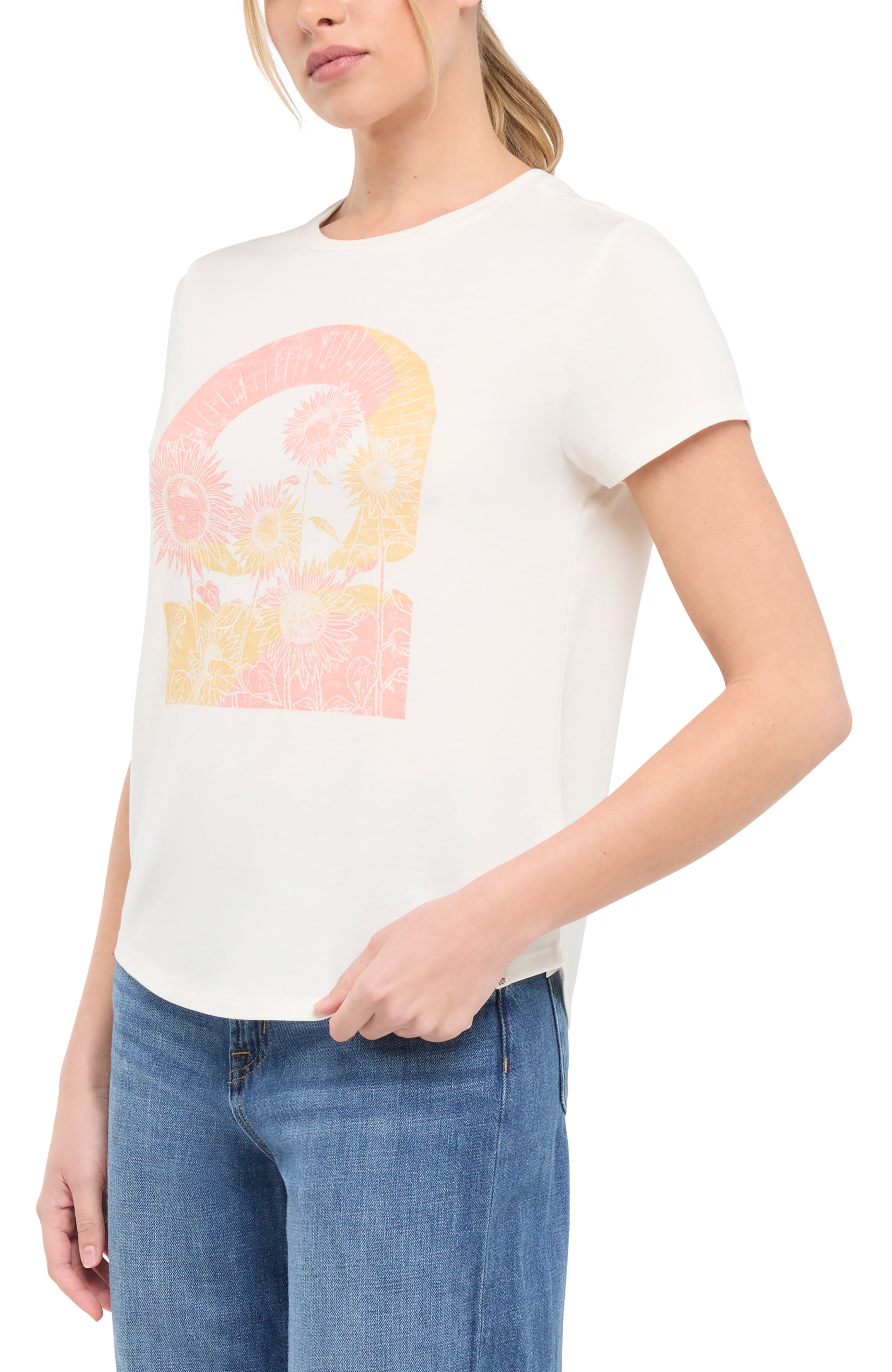 Side view of woman wearing a white t-shirt with colorful tie-dye sunflowers graphic on a white background. 