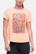 Front view of woman wearing a peach t-shirt with floral graphic on a light gray background. #color_heather-melon-ice-daisies-in-the-sun
