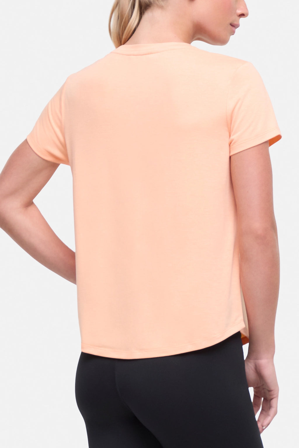 Back view of woman wearing a peach t-shirt with floral graphic on a light gray background. #color_heather-melon-ice-daisies-in-the-sun