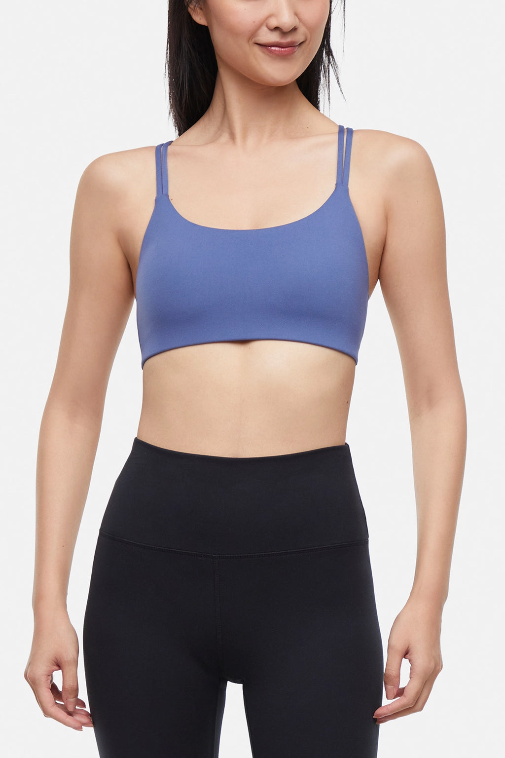 Front view of woman wearing a blue sports bra and black leggings on a white background. #color_gray-blue