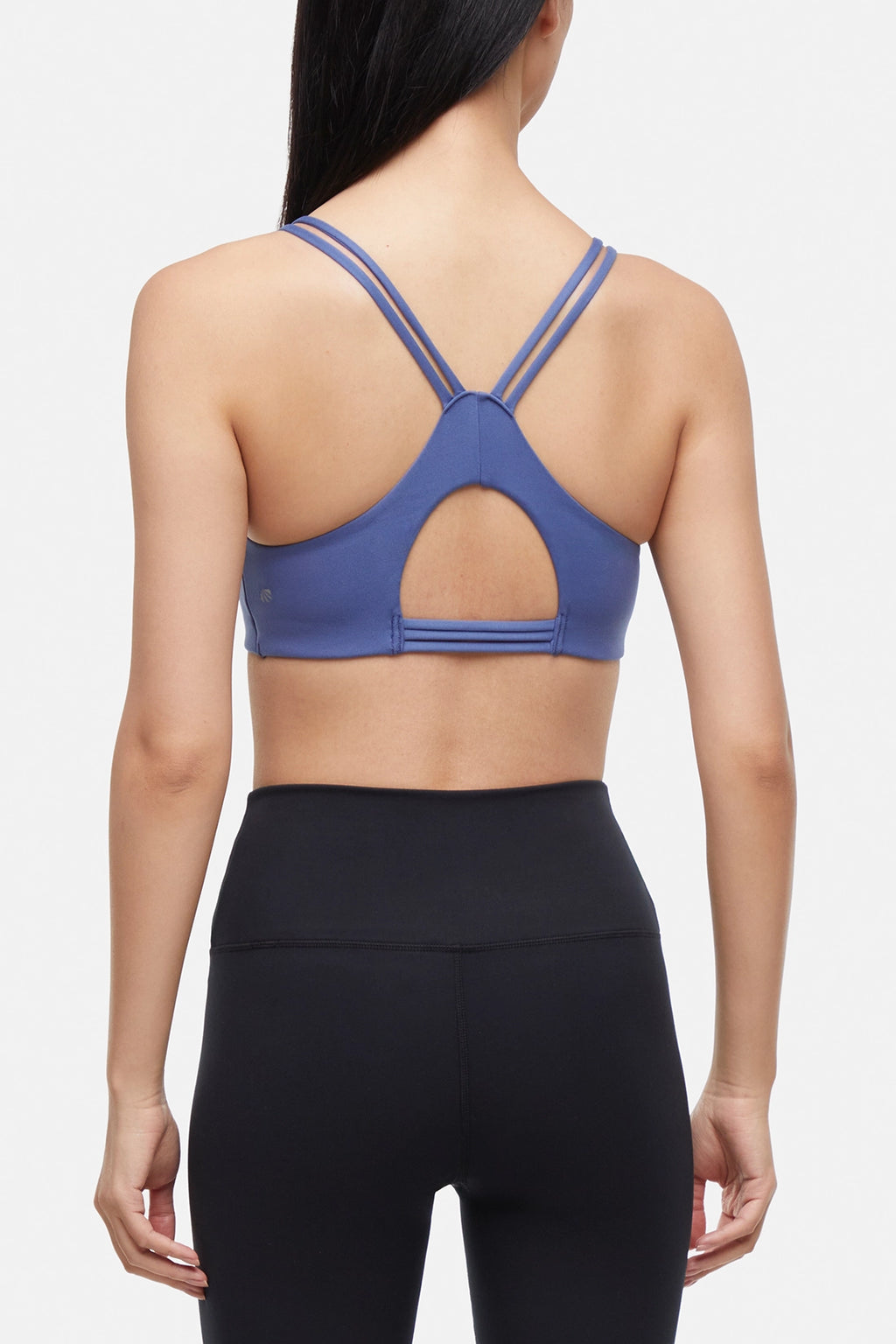 Back view of blue sports bra with crisscross straps and keyhole cutout detail on a plain background. #color_gray-blue