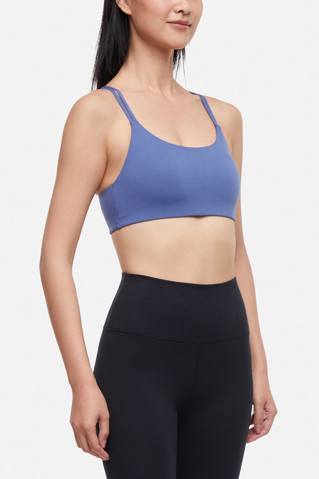 Front view of woman wearing a blue sports bra and black leggings on a white background. #color_gray-blue