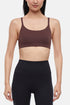 Front view of woman wearing a brown sports bra and black leggings on a white background. 