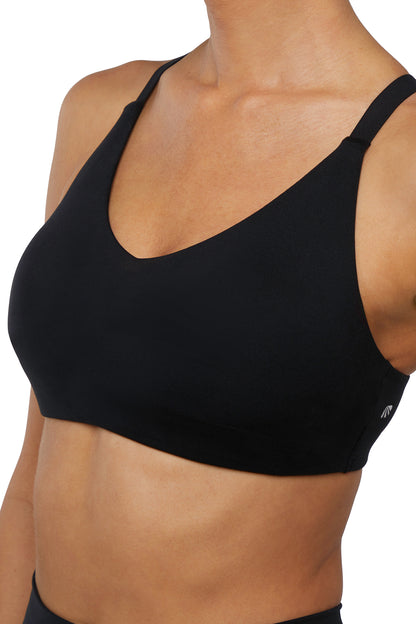 Close up front view of woman wearing a black sports bra and leggings on a white background. 