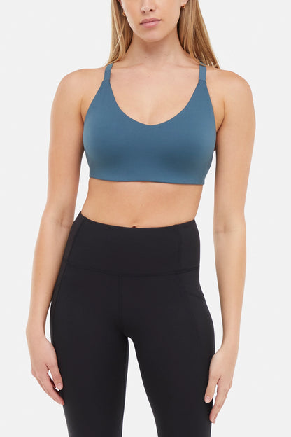 Front view of woman wearing a blue sports bra and leggings on a white background. 