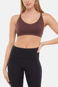 Front view of woman wearing a brown sports bra and black leggings on a white background. #color_french-roast