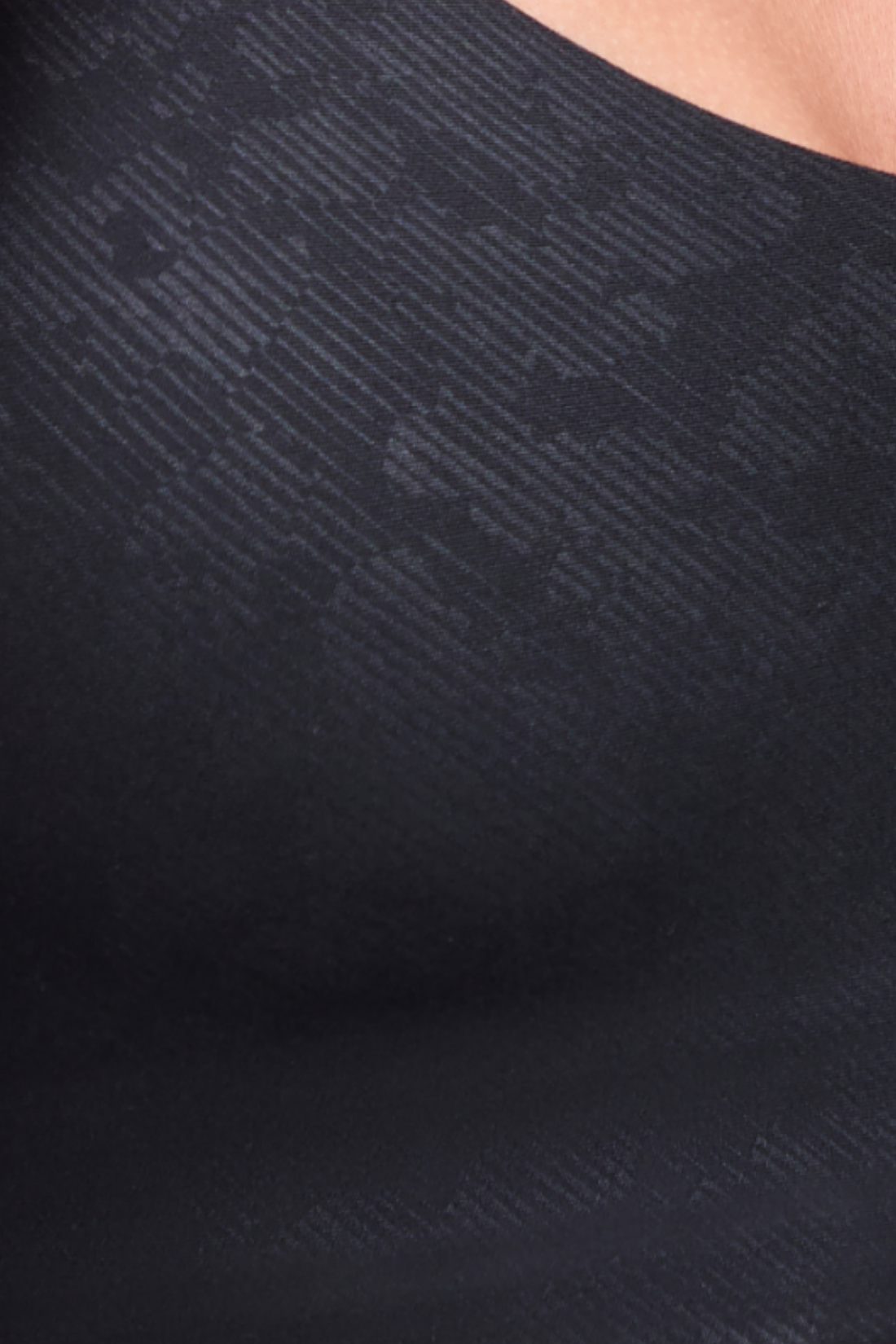 Close-up of a black textured top with a subtle diagonal jacquard pattern, showing a portion of the wearer's neck and shoulder. #color_black-linear-animal-camo