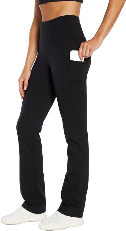 Woman wearing black high-waisted pants with hand in side pocket on a white background. 