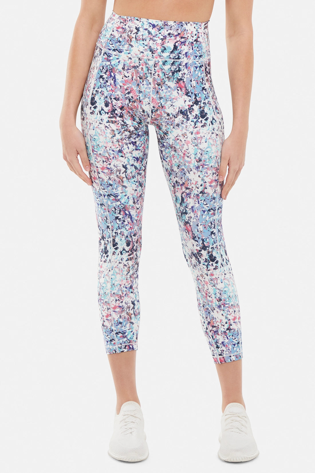 Front view of woman wearing colorful floral capri on a white background.