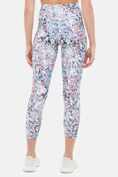 Back view of woman wearing colorful floral capris on a white background. 