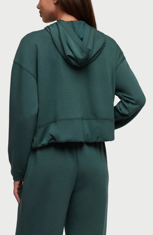 A woman shown from the back wearing a dark green cropped hooded sweatshirt and matching sweatpants against a plain white background. #color_garden-topiary