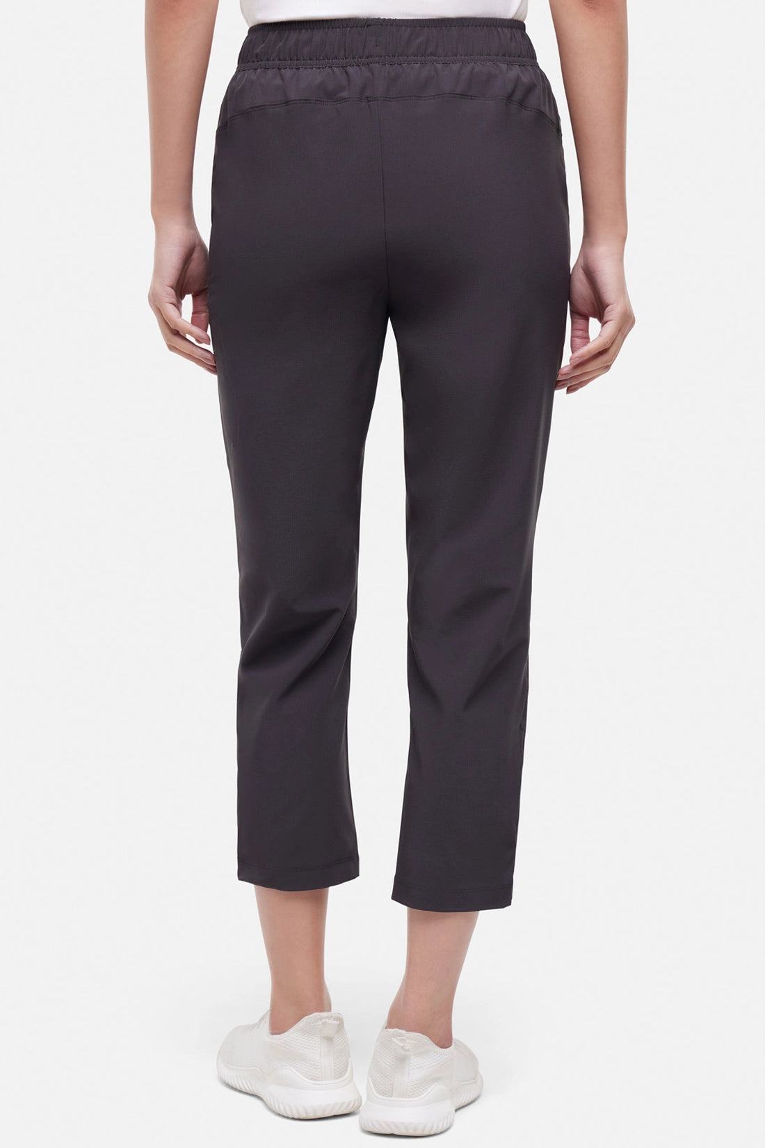 Back view of woman wearing black cropped pants with a white drawstring on a white background.
