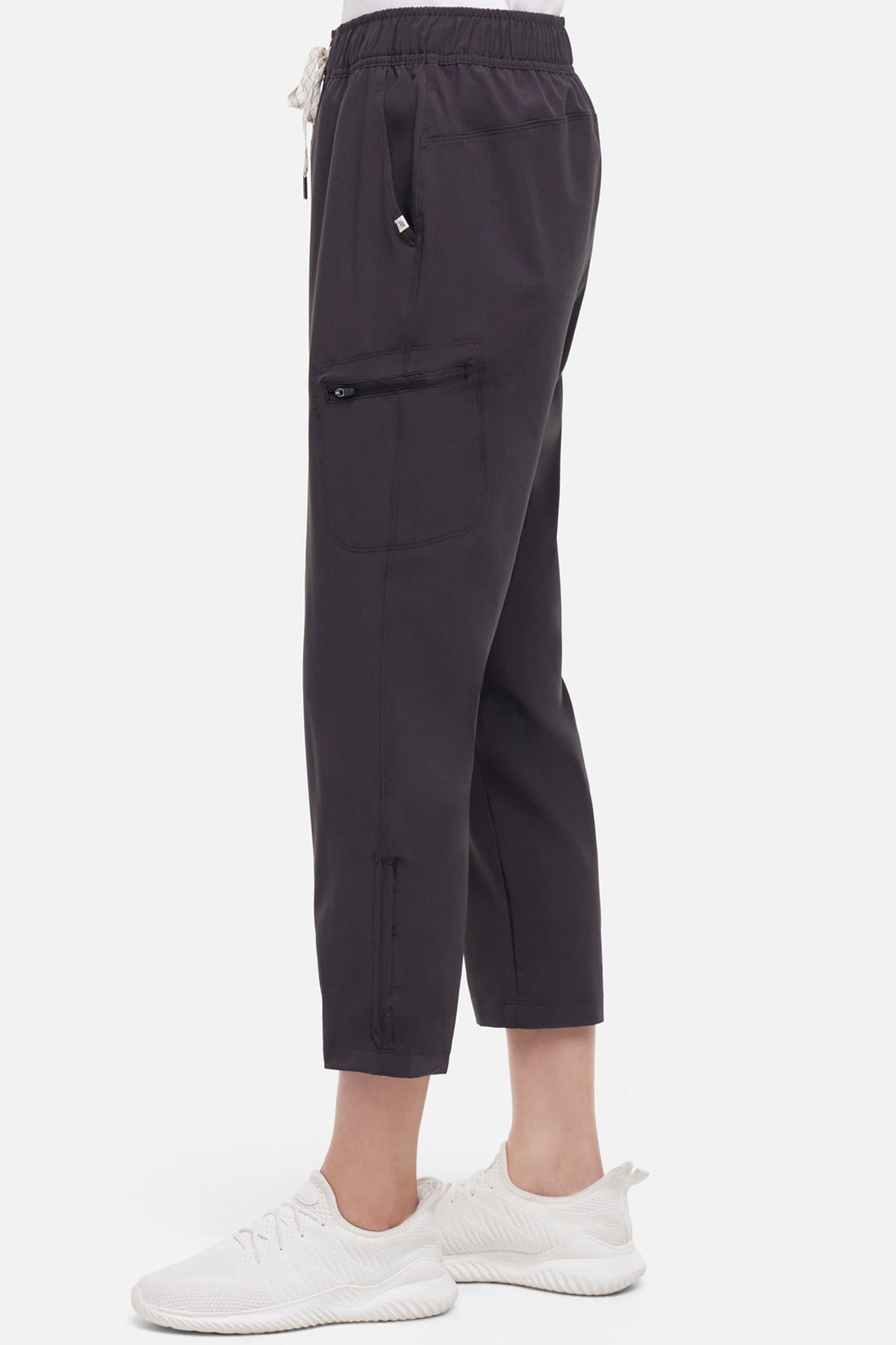 Side view of woman wearing black cropped pants with a white drawstring on a white background.