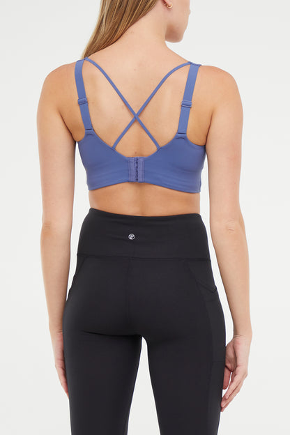Back of Woman wearing a blue sports bra and black leggings on a white background. 