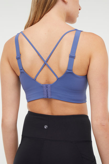 Close up back of Woman wearing a blue sports bra and black leggings on a white background. 