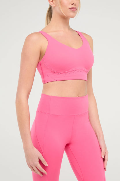 Side view of woman wearing a pink sports bra and matching pink leggings on a white background.  