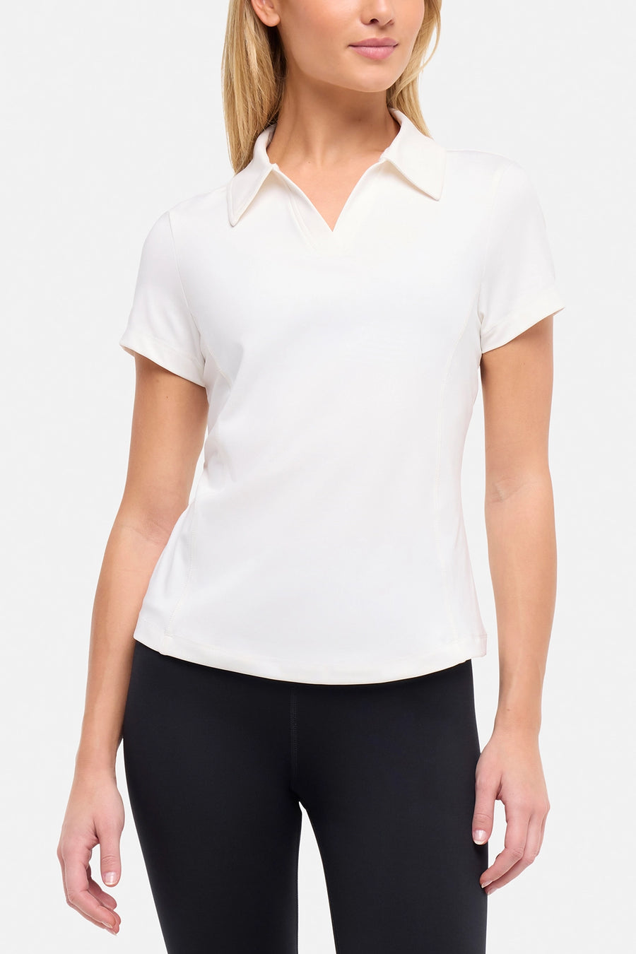 Front view of woman wearing a white short-sleeve polo shirt and black pants on a plain background. #color_sugar-swizzle