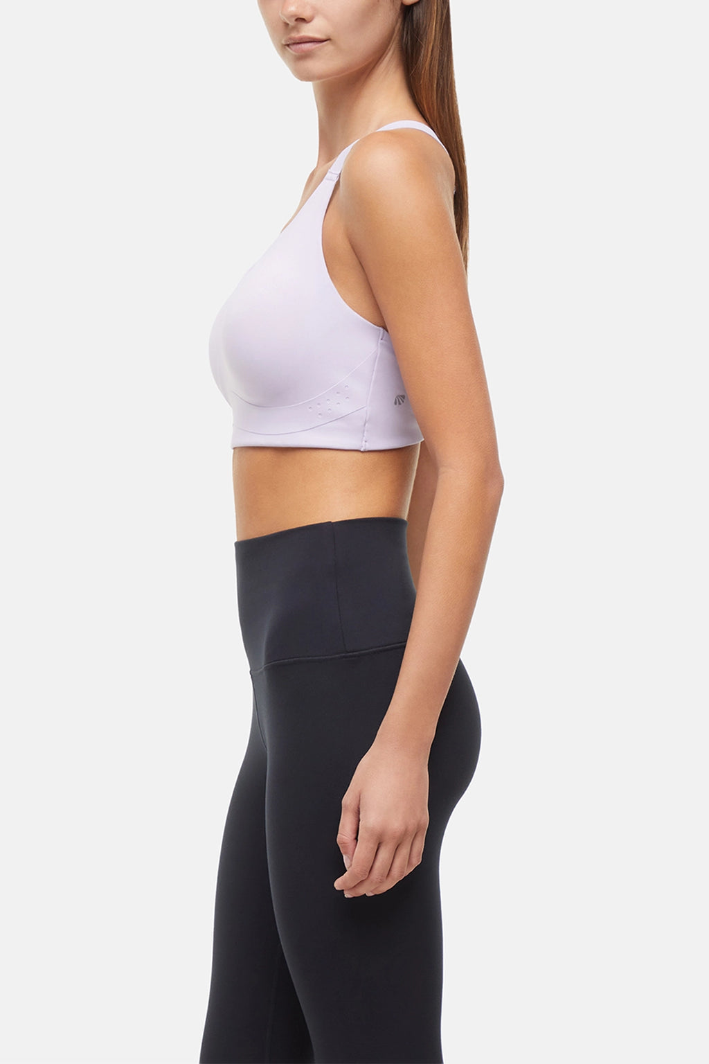 Side view of woman wearing a lilac sports bra and black leggings on a light gray background. #color_lilac-clematis