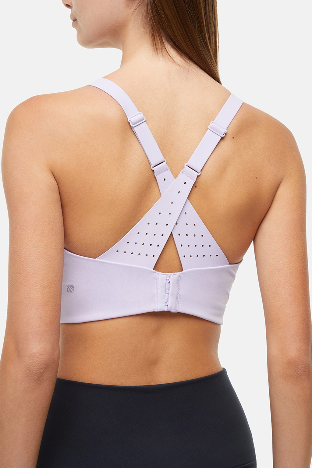 Close up back view of woman wearing a light purple sports bra with criss-cross straps and black leggings on a white background. #color_lilac-clematis