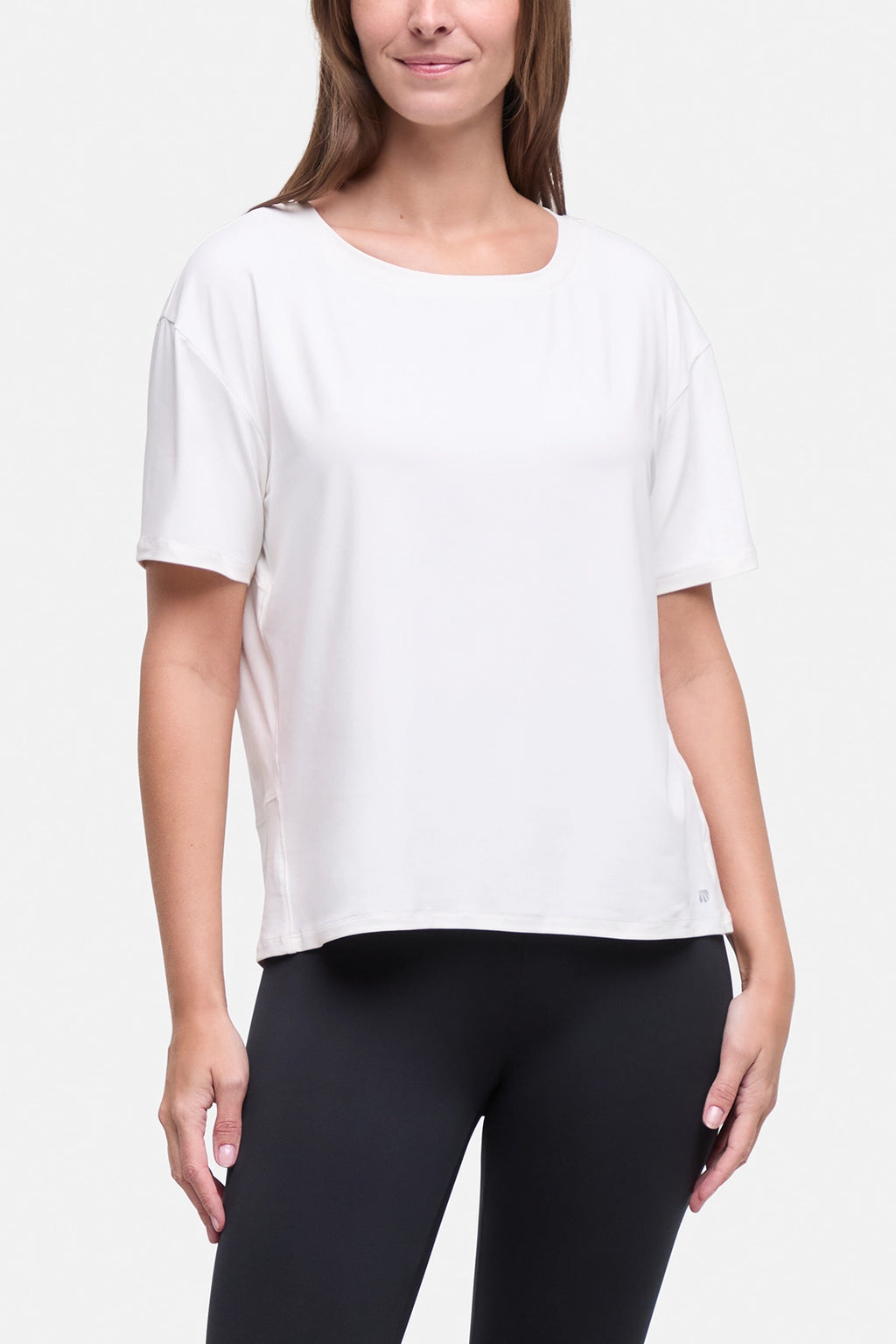 A woman wearing a white short-sleeve scoop-neck athletic top and black leggings, shown from the nose down against a light gray studio background. #color_sugar-swizzle