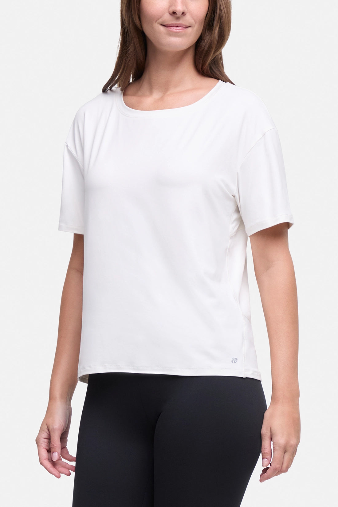 A woman wearing a white short-sleeve crewneck athletic top and black leggings, shown from the nose down against a light gray studio background. #color_sugar-swizzle